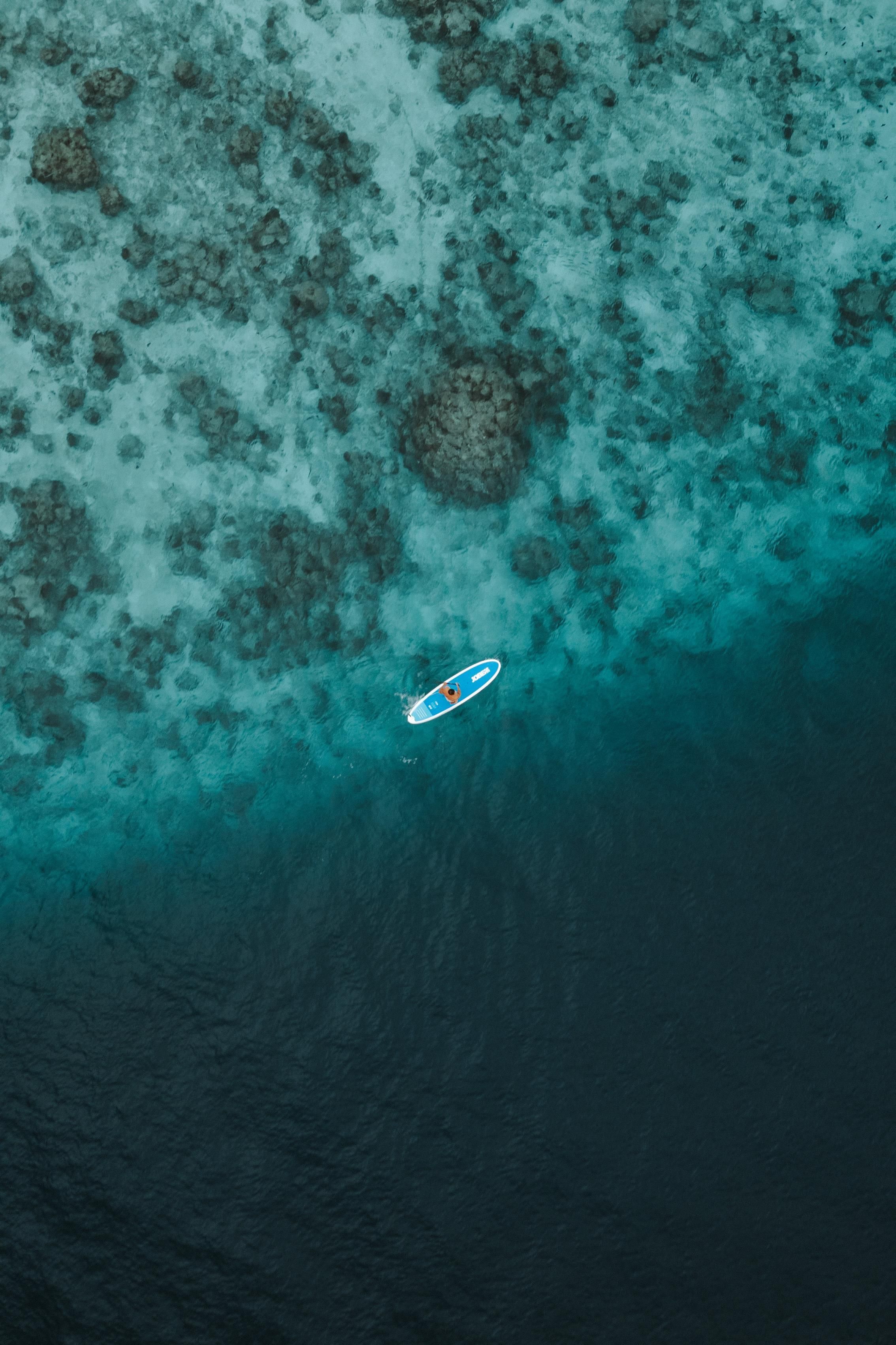 An aerial view of a beach with clear turquoise waters and scattered rocks.