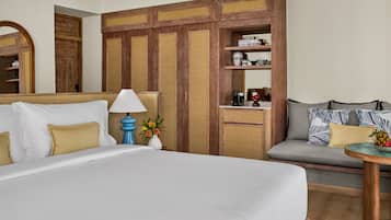 Une chambre d’hôtel avec un grand lit, un canapé, une petite table, une machine à café et une étagère avec des livres et des objets décoratifs.