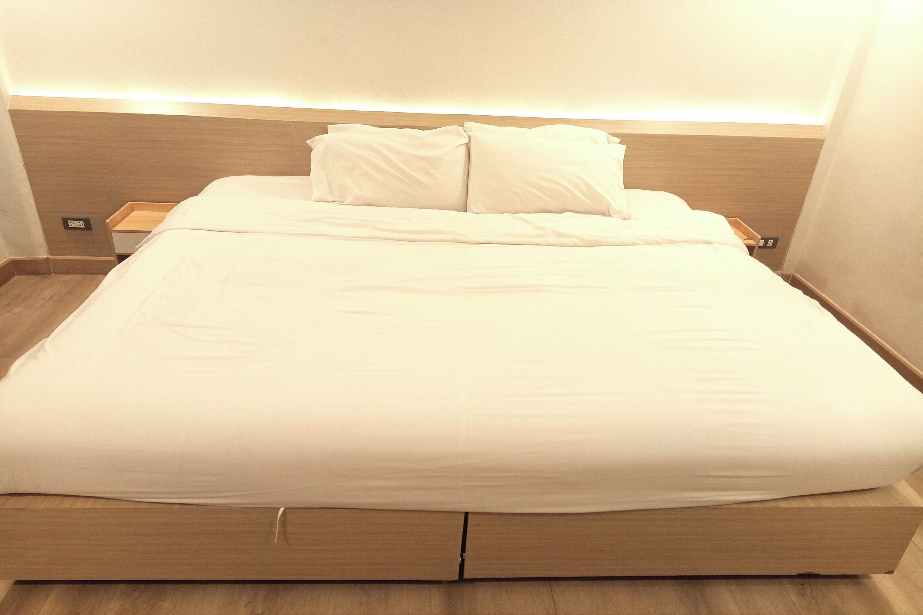 A neatly made bed with a wooden headboard and a bedside table with a lamp.
