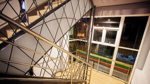 A modern staircase with a geometric metal railing and a view of a colorful street below. - Smile Place Hotel Chiang Rai (Chiang Rai)