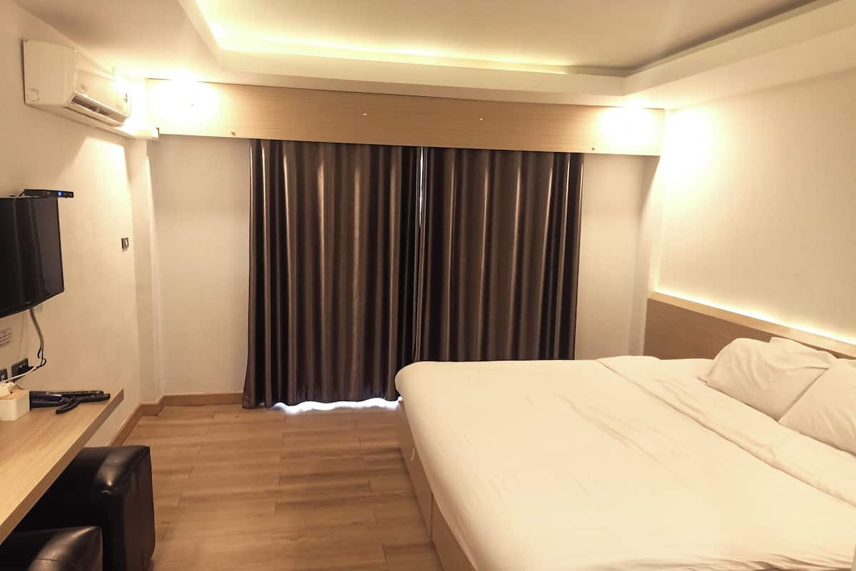 A hotel room with a bed, a desk with a computer, and a TV.