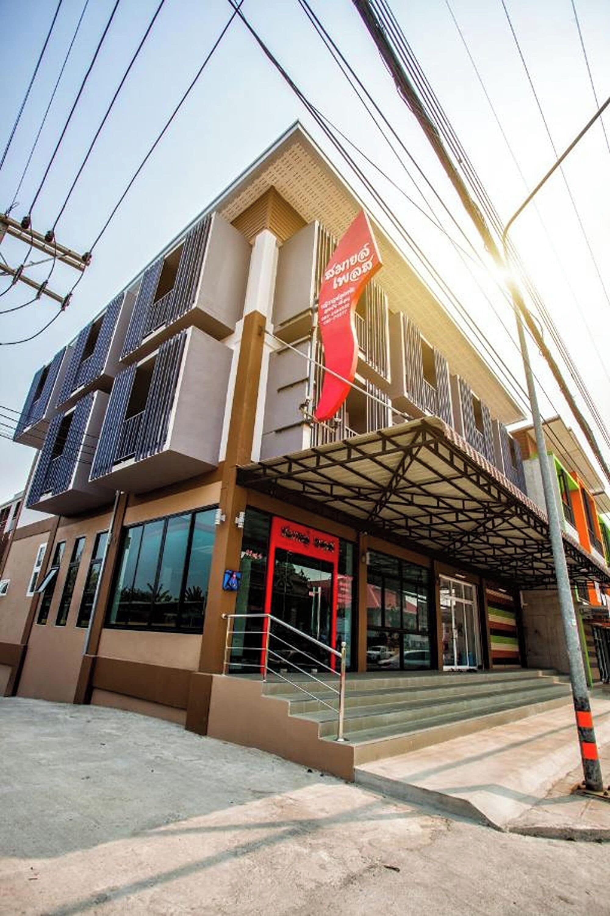 A modern building with a covered entrance, large windows, and a red banner.