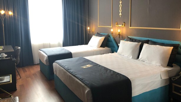 A hotel room with two beds, a desk, and a chair. - My House Otel (Samsun)