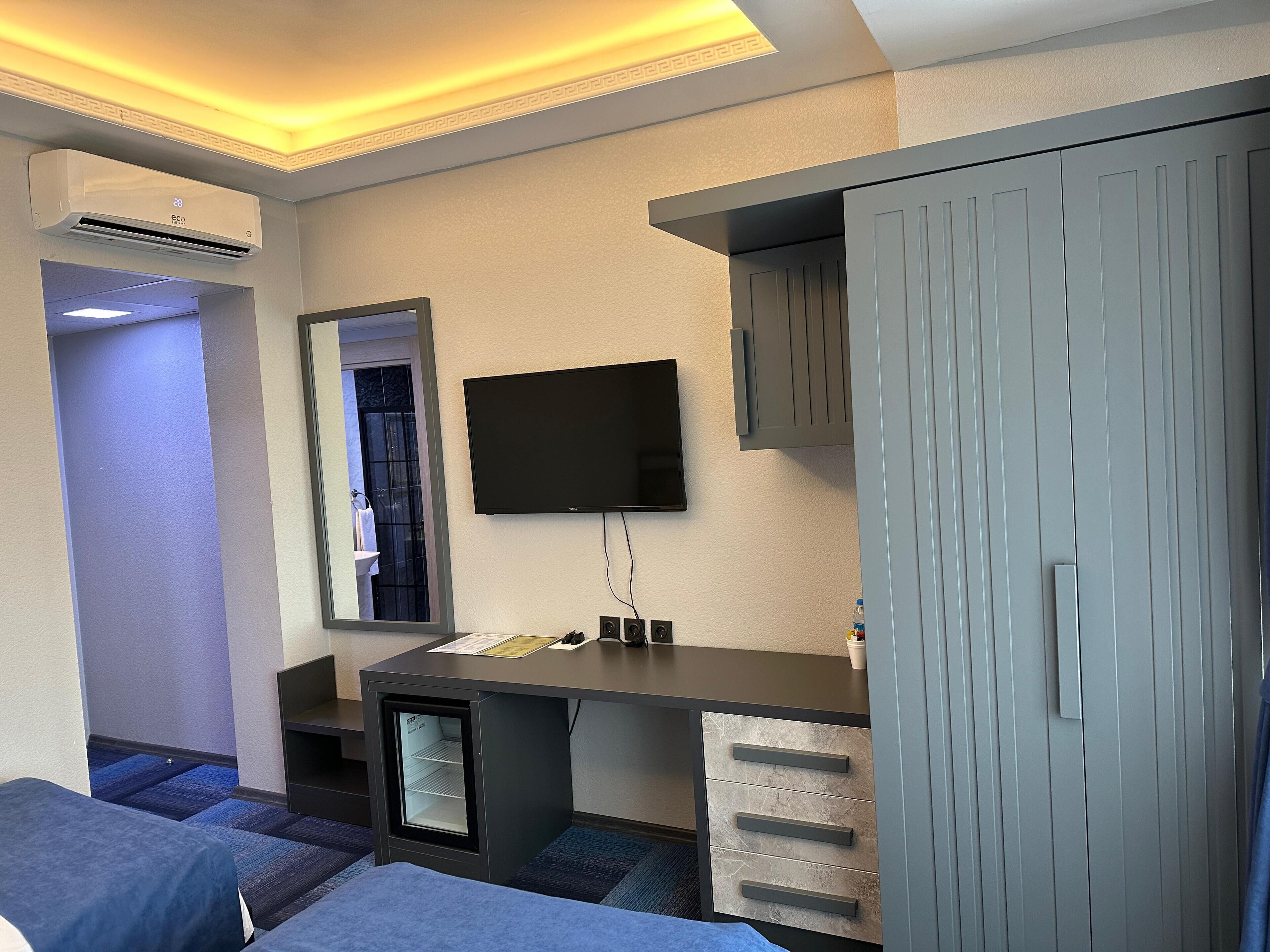Ein Hotelzimmer mit einem Bett, einem Schreibtisch mit Schubladen, einem Fernseher und einem Kleiderschrank.