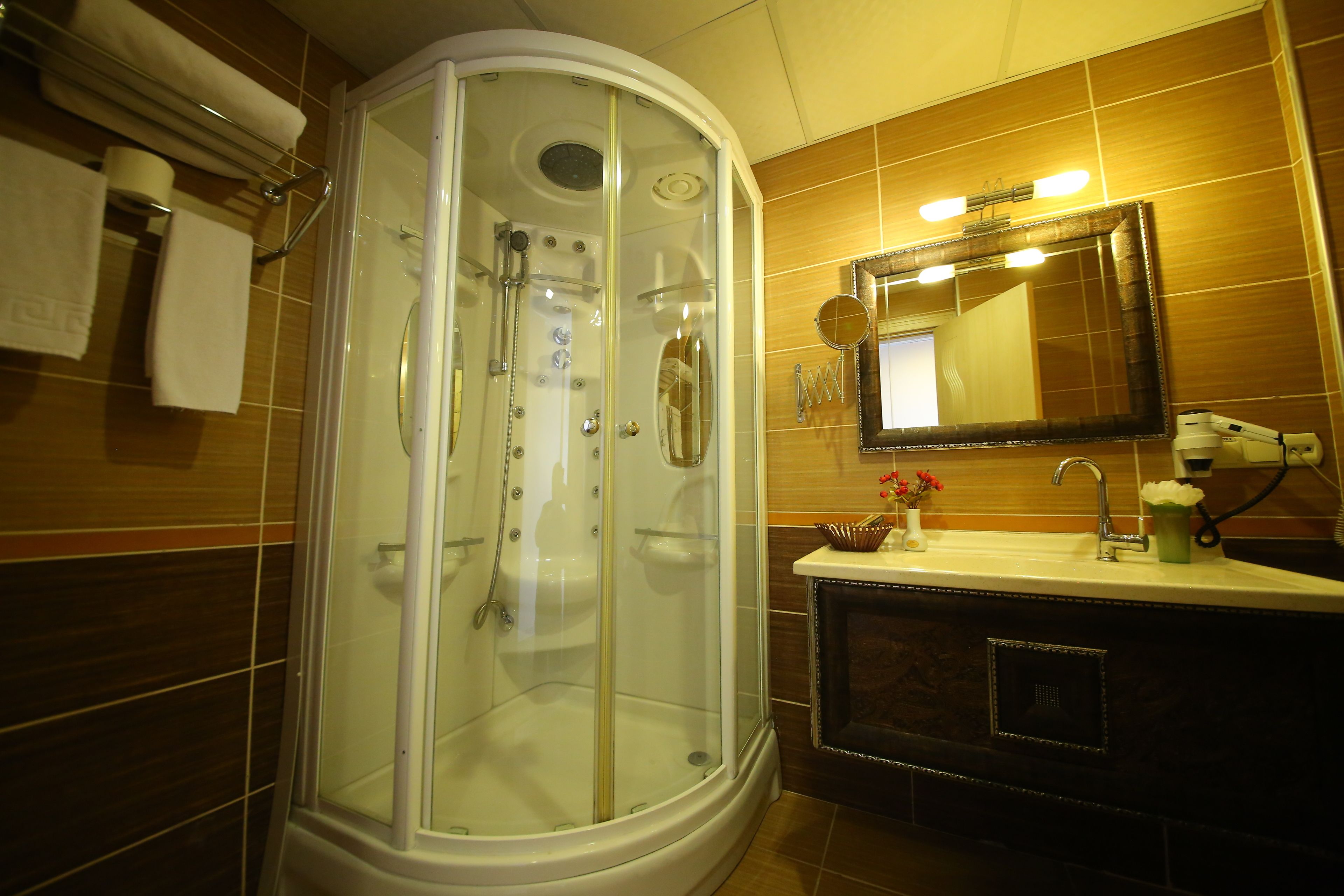 Un baño con ducha envuelta en vidrio, un lavabo con espejo y artículos de aseo.