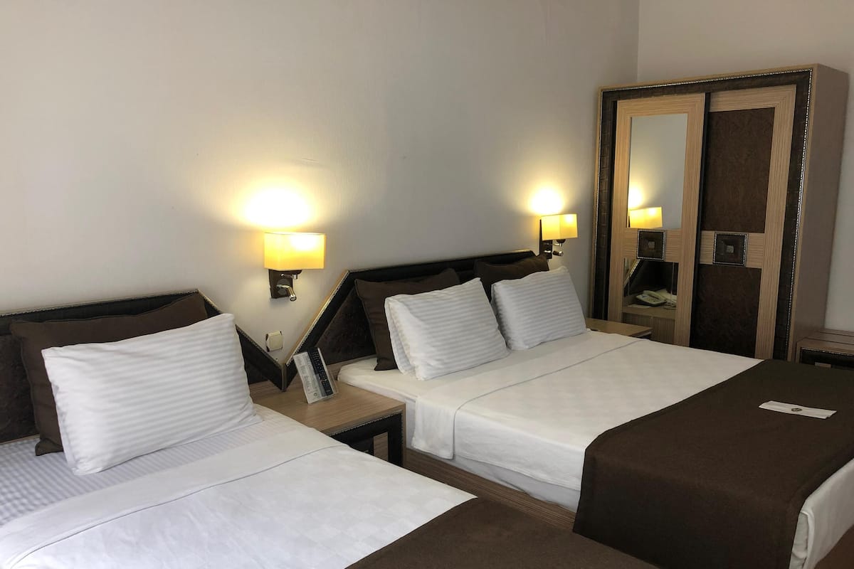 Hotellihuone, jossa on kaksi sänkyä, vaatekaappi ja kaksi yöpöytälamppua.