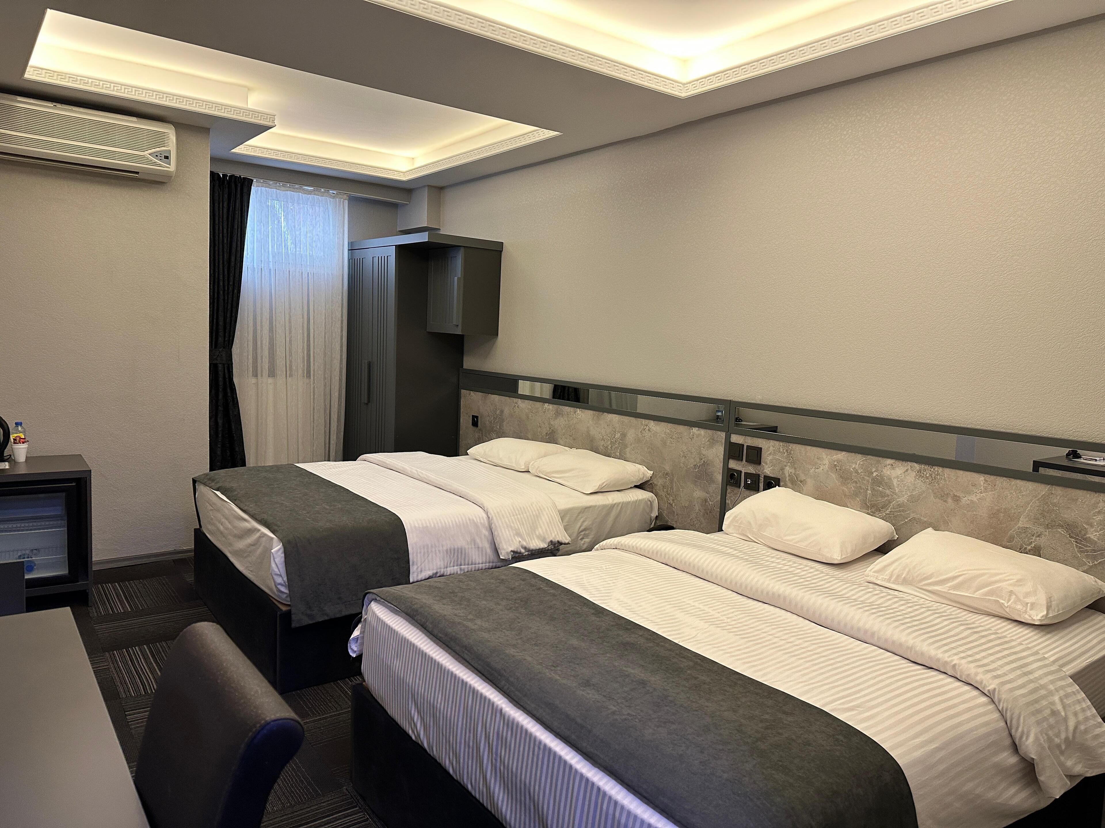 Una habitación de hotel con dos camas, un escritorio, una silla y un televisor.
