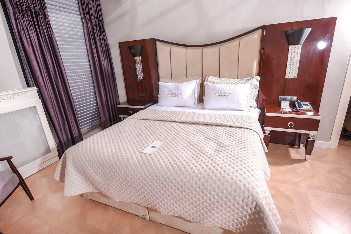 Hotellihuone, jossa on sänky, yöpöytä, työpöytä ja tuoli.
