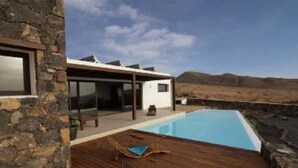 Une maison moderne dotée d’une piscine, de murs en pierre et d’une terrasse en bois.
