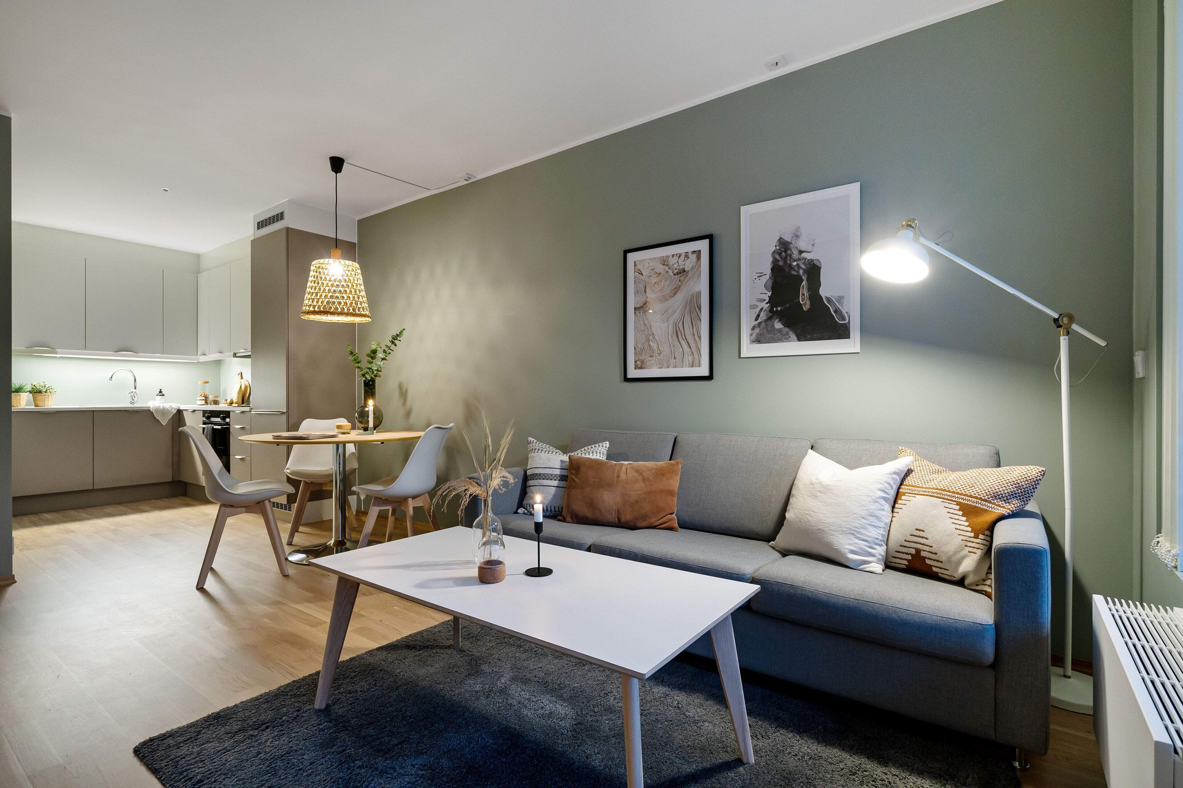 Una sala de estar moderna con un sofá gris, una mesa de centro blanca y un comedor con sillas y una mesa.