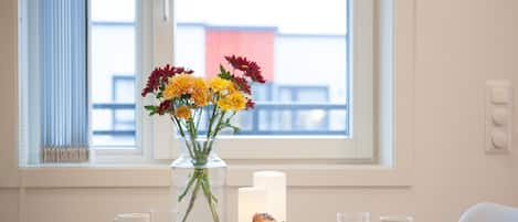 Une table avec un vase de fleurs, une bougie, des croissants et un journal.