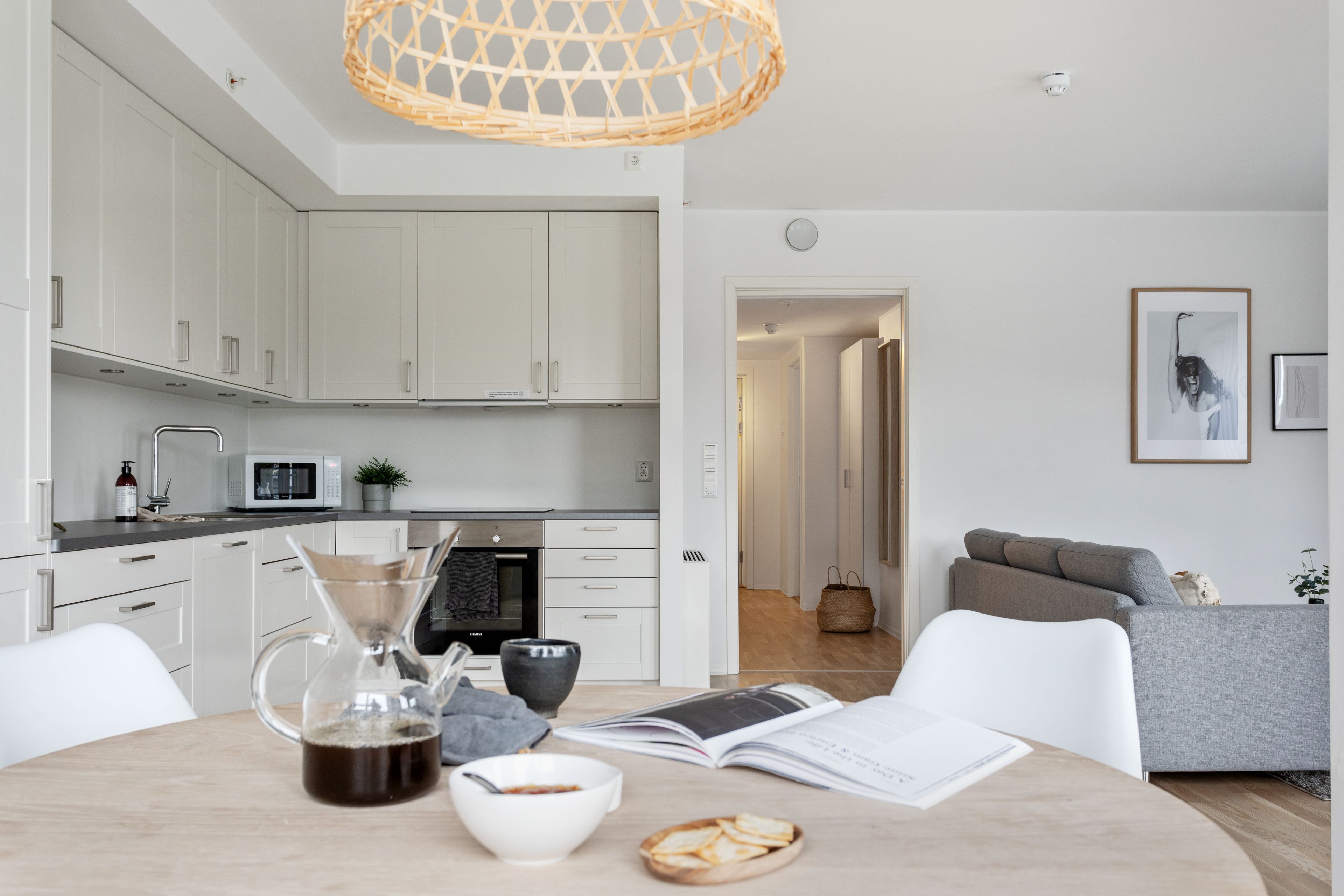 A modern kitchen with white cabinets, a microwave, and a coffee maker on the counter.