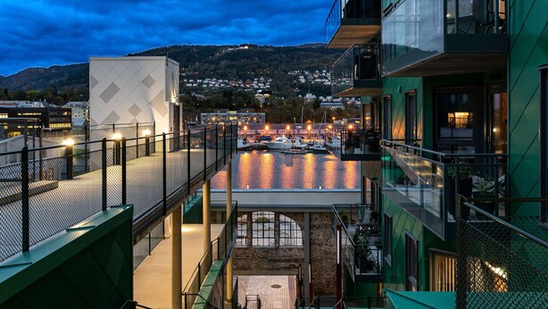 Un bâtiment moderne doté d’une façade en verre, d’un escalier menant à un niveau supérieur et offrant une vue sur le bord de l’eau, avec des bateaux.