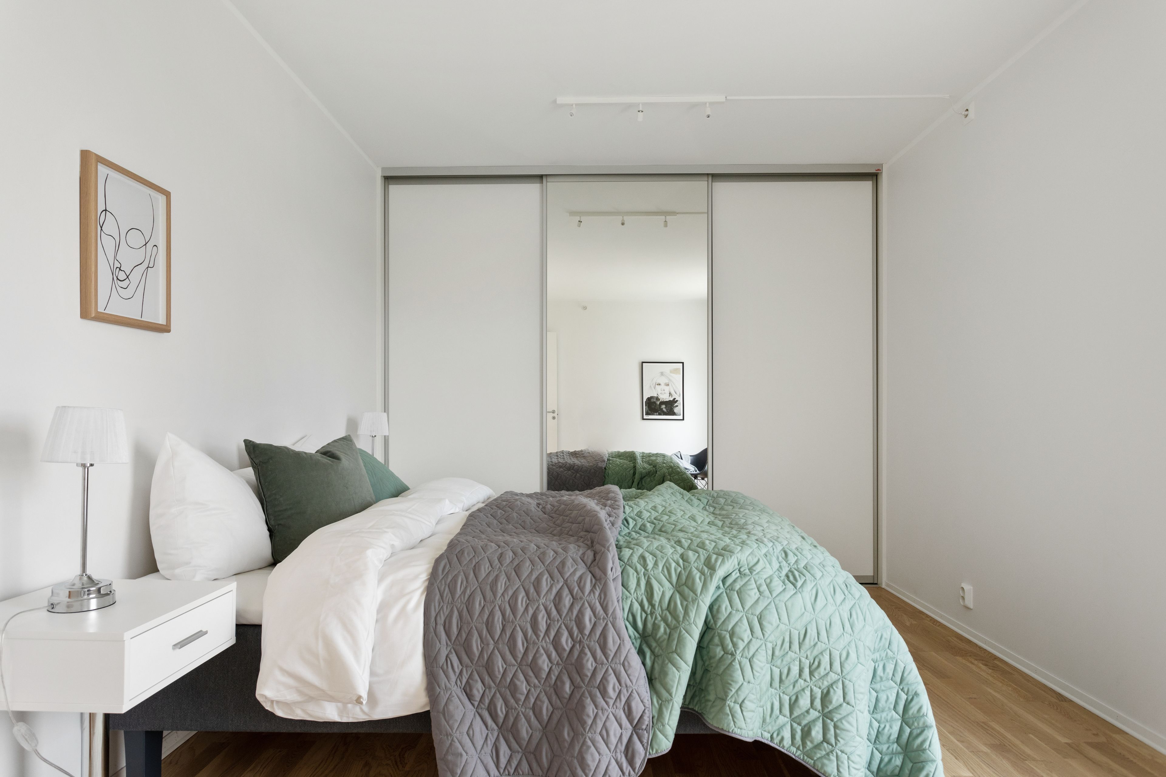 A modern bedroom with a bed, bedside table, and a wardrobe.