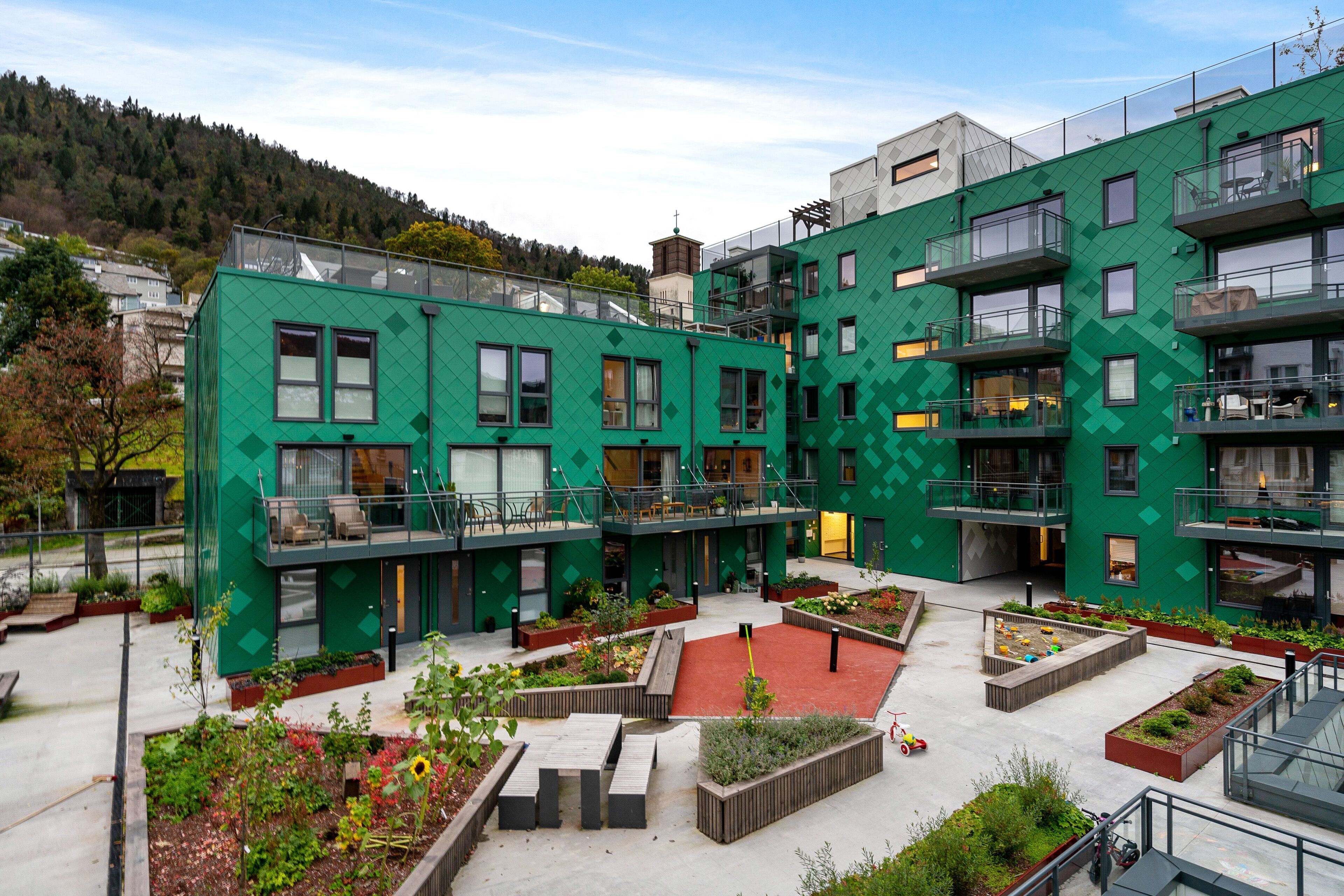 A modern building with multiple balconies and a courtyard with planters.