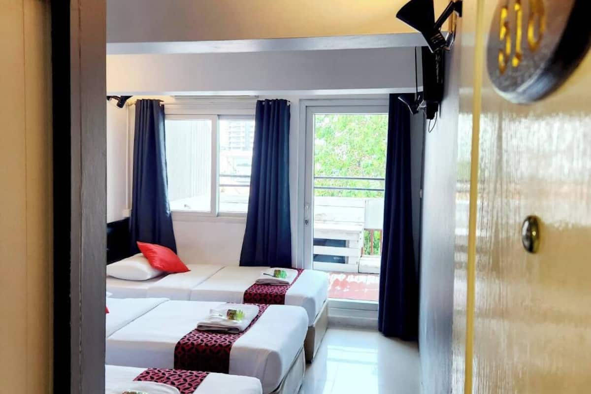 Une chambre d’hôtel avec deux lits, une porte coulissante donnant sur un balcon et un luminaire fixé au plafond.