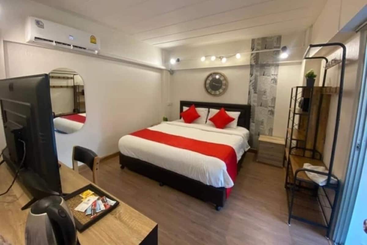 Une chambre d’hôtel comprenant un lit, un bureau avec un ordinateur, une chaise, une télévision et une petite table.