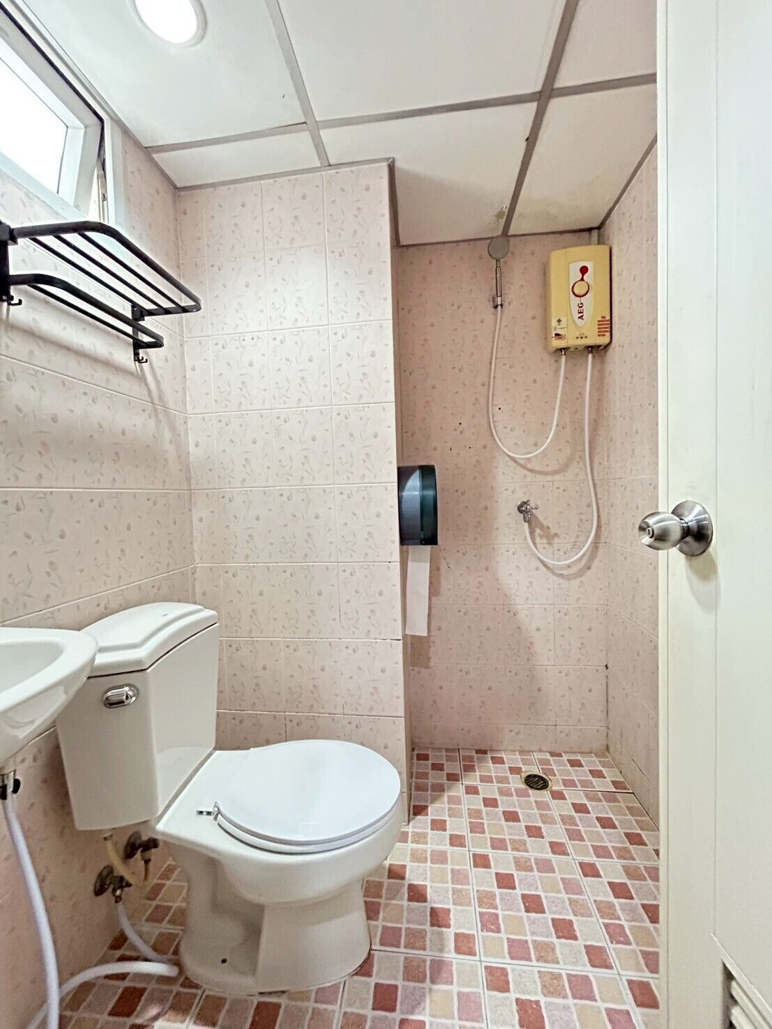 A small bathroom with a toilet, sink, and shower.