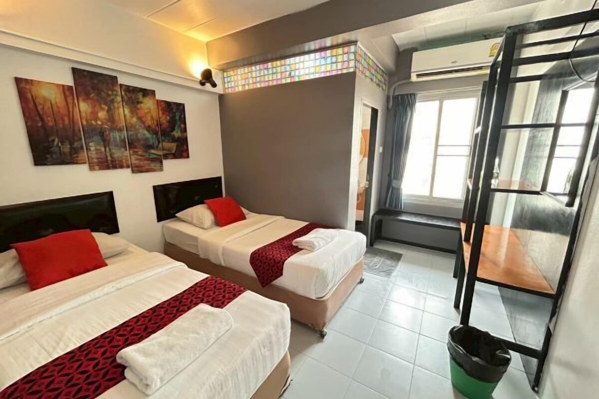 A hotel room with two beds, a large window, and a painting on the wall.