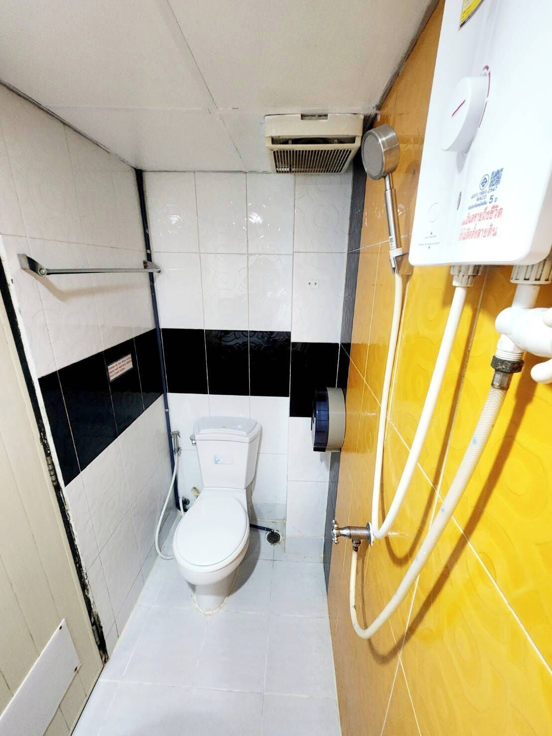 Ein kleines, kompaktes Badezimmer mit Toilette, Duschkabine und einem Händetrockner.