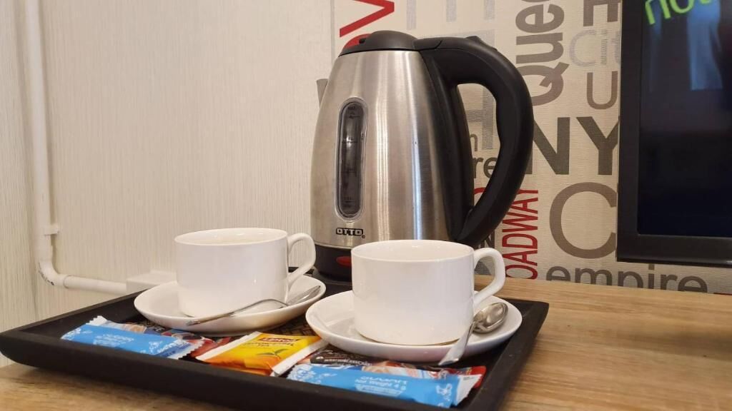 Una safata amb dues tasses i platets blancs, una tetera elèctrica platejada i una selecció d'aperitius envasellats.