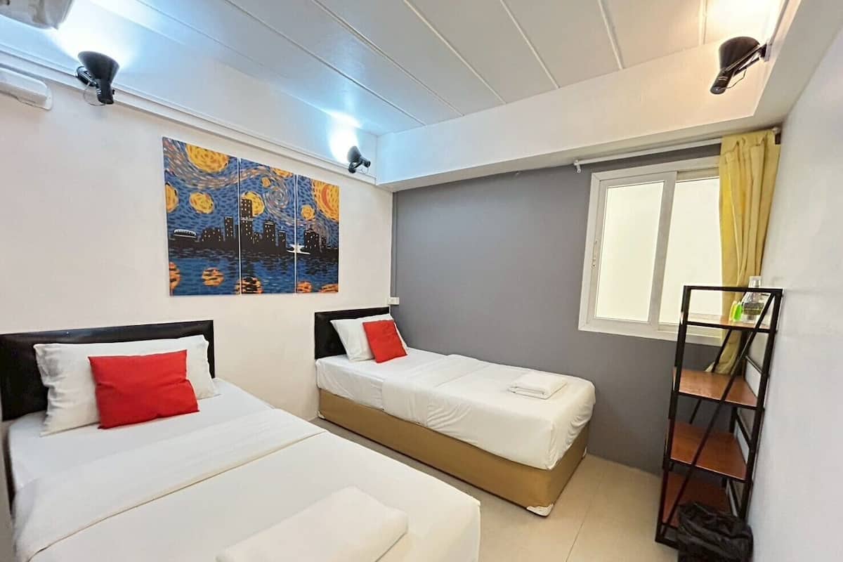 Une chambre d’hôtel avec deux lits, un tableau au mur, une fenêtre avec des rideaux et une étagère avec des articles de toilette.