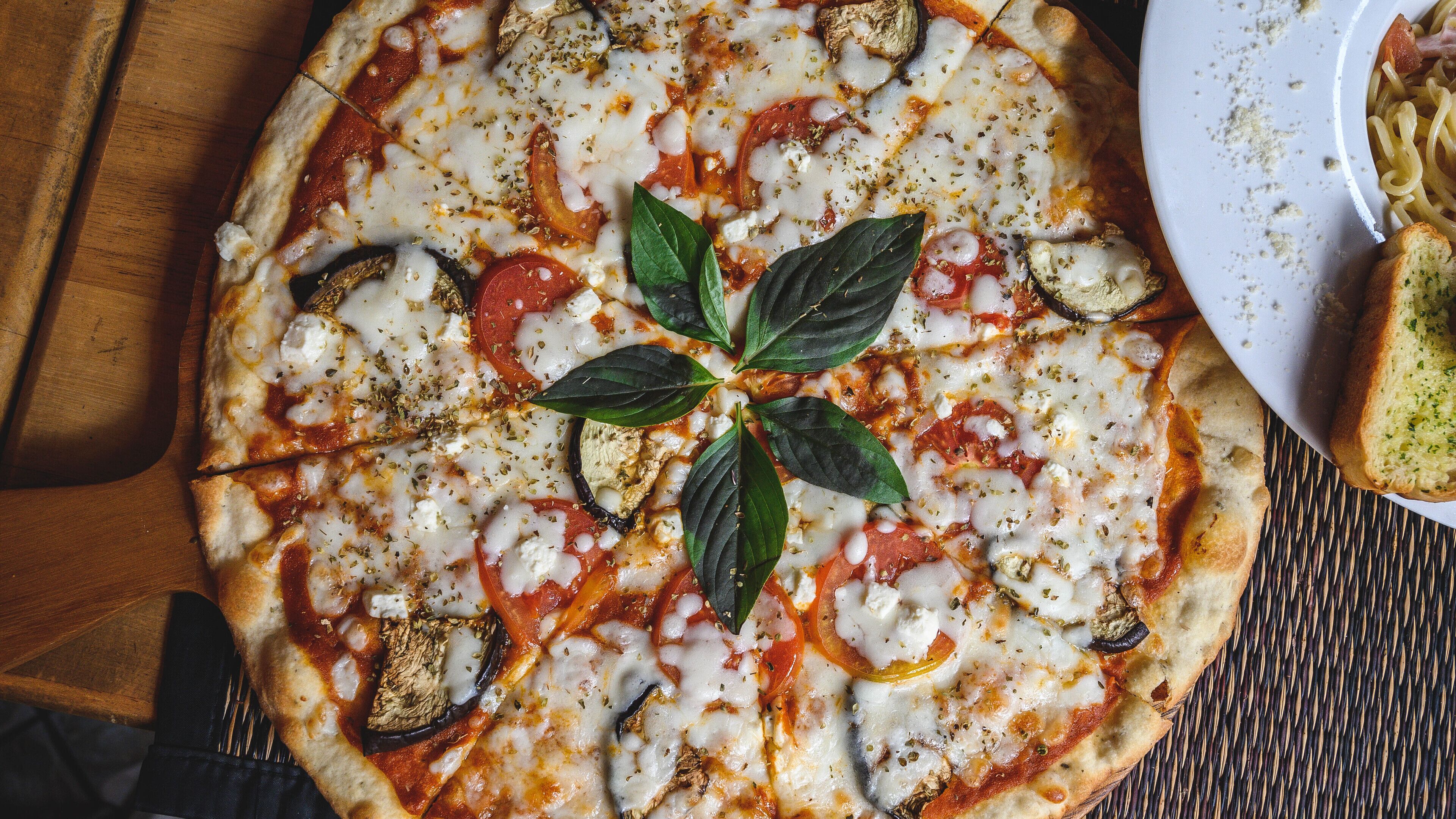 A pizza with toppings and a basil leaf garnish on a wooden surface.