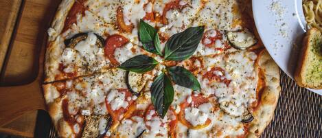 A pizza with toppings and a basil leaf garnish on a wooden surface.