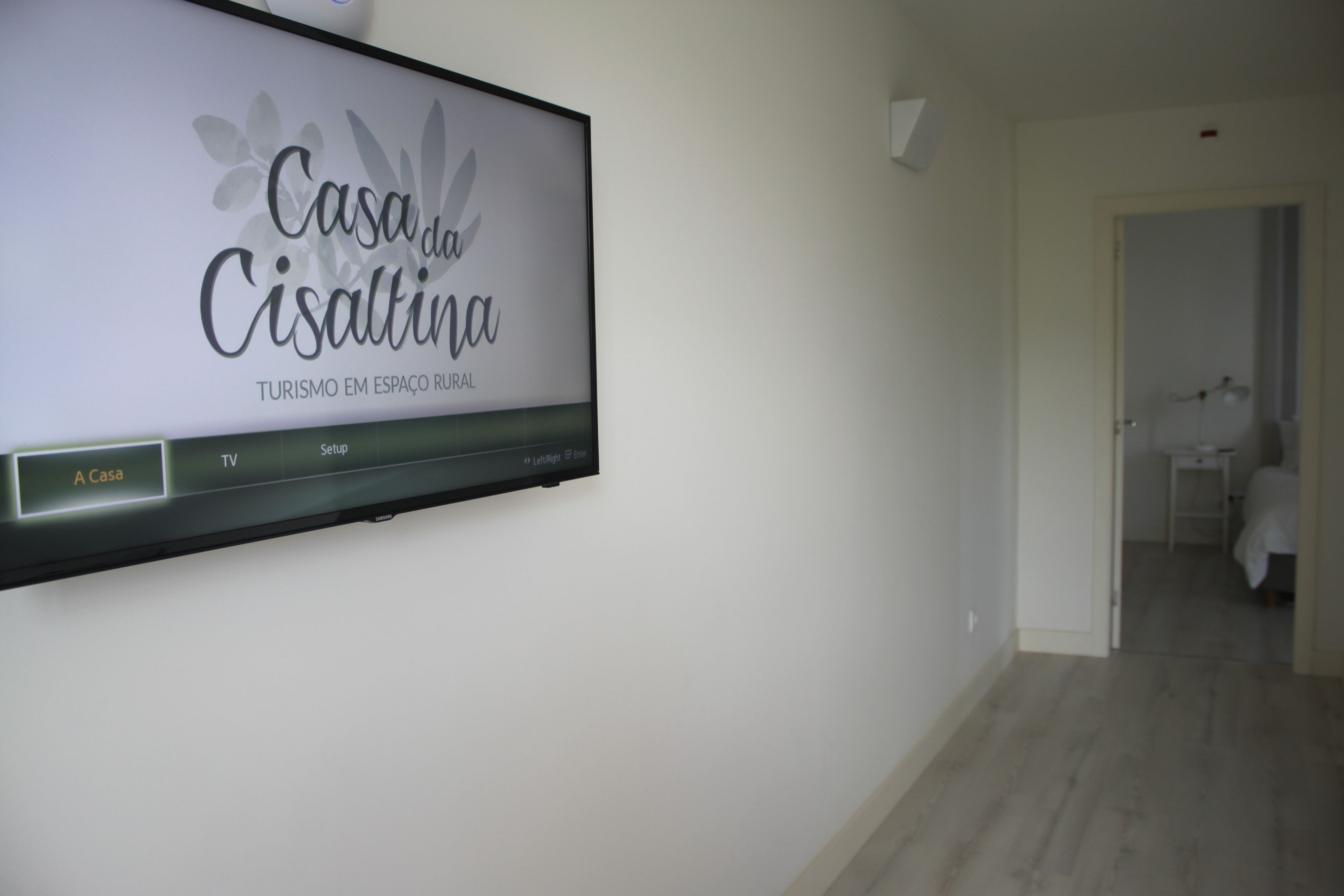 A hotel sign with the name "Casa da Cisaltina" and a TV mounted on the wall.