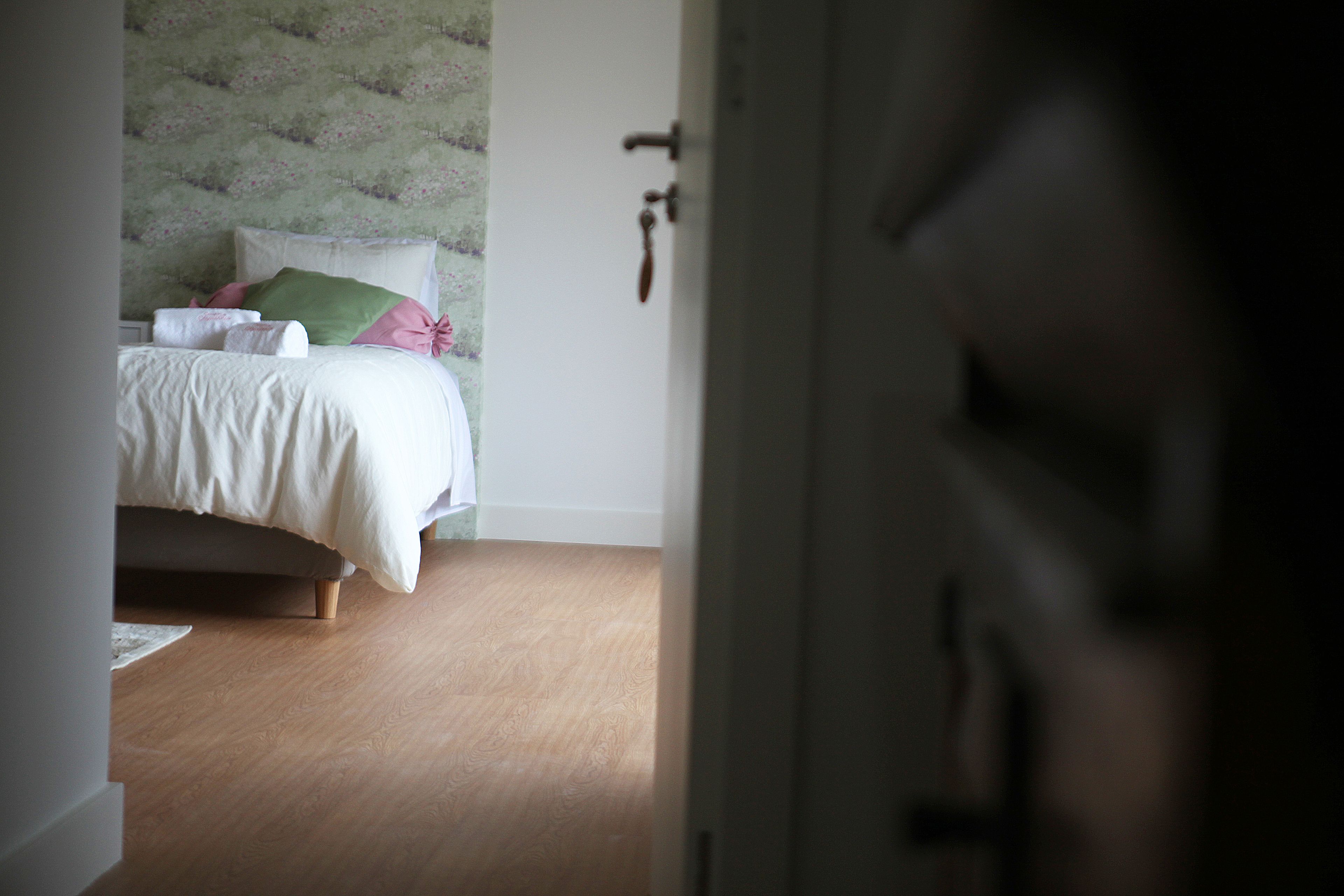 A bedroom with a bed, pillows, and a door.