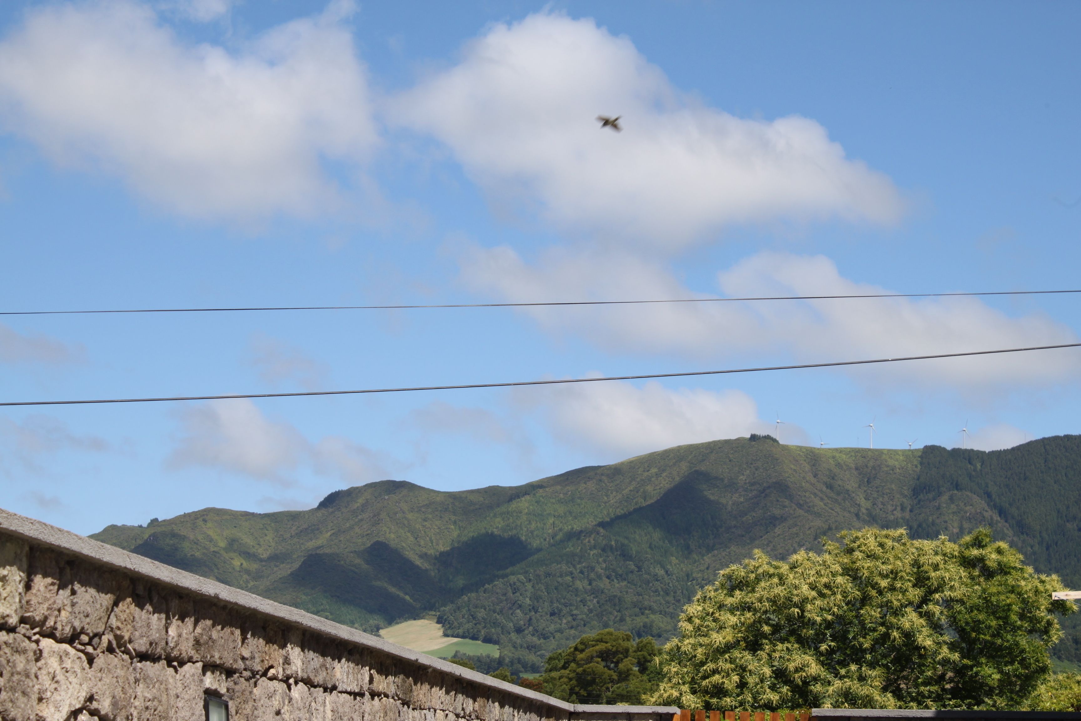 A view of a mountain range with a clear sky and a single airplane flying overhead.