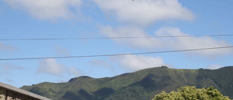 A view of a mountain range with a clear sky and a single airplane flying overhead.