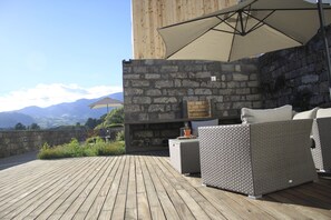 Een houten terras met rieten meubels en een stenen muur.