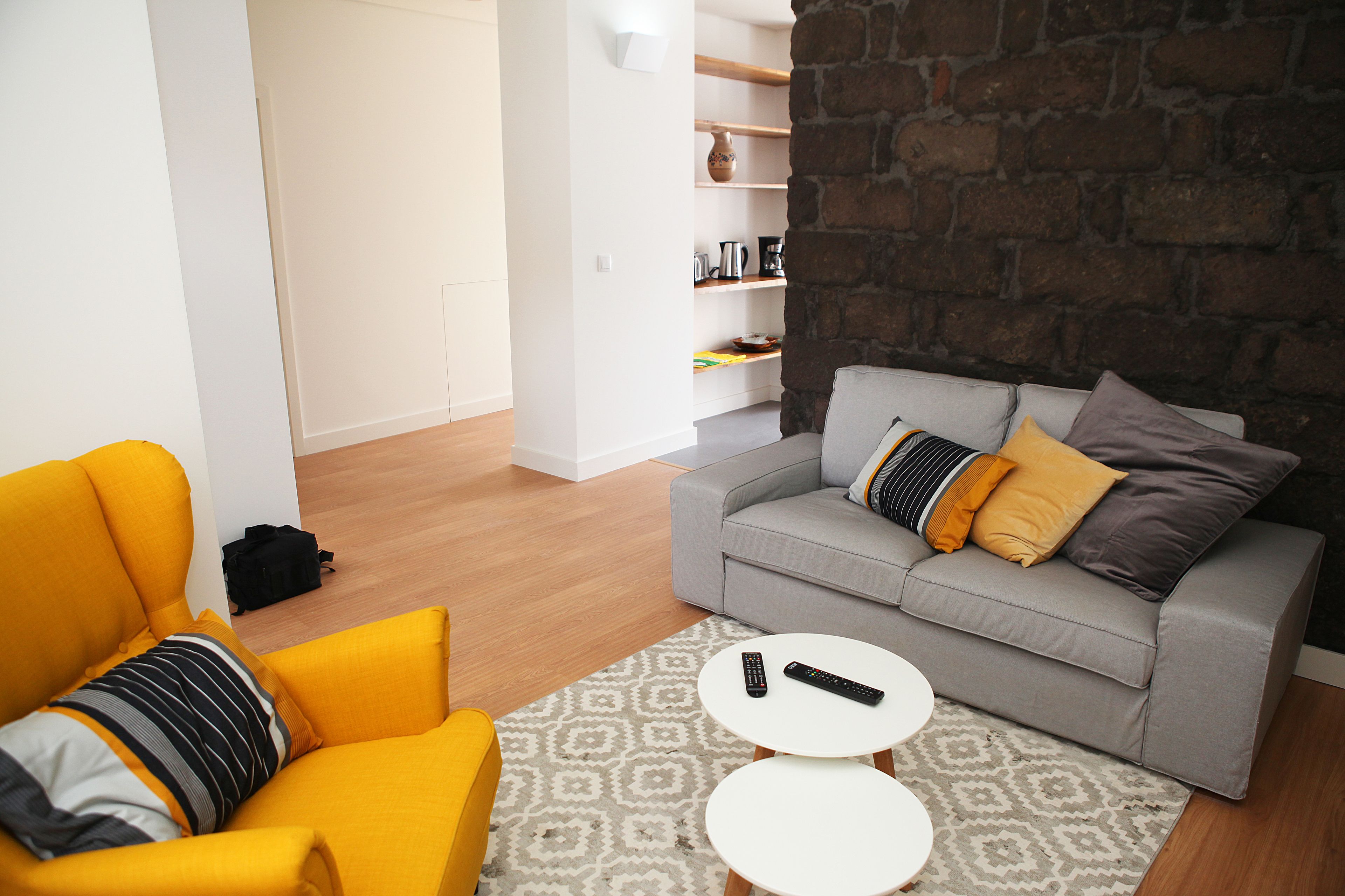 Una sala de estar moderna con un sofá gris, un sillón amarillo y una alfombra estampada.
