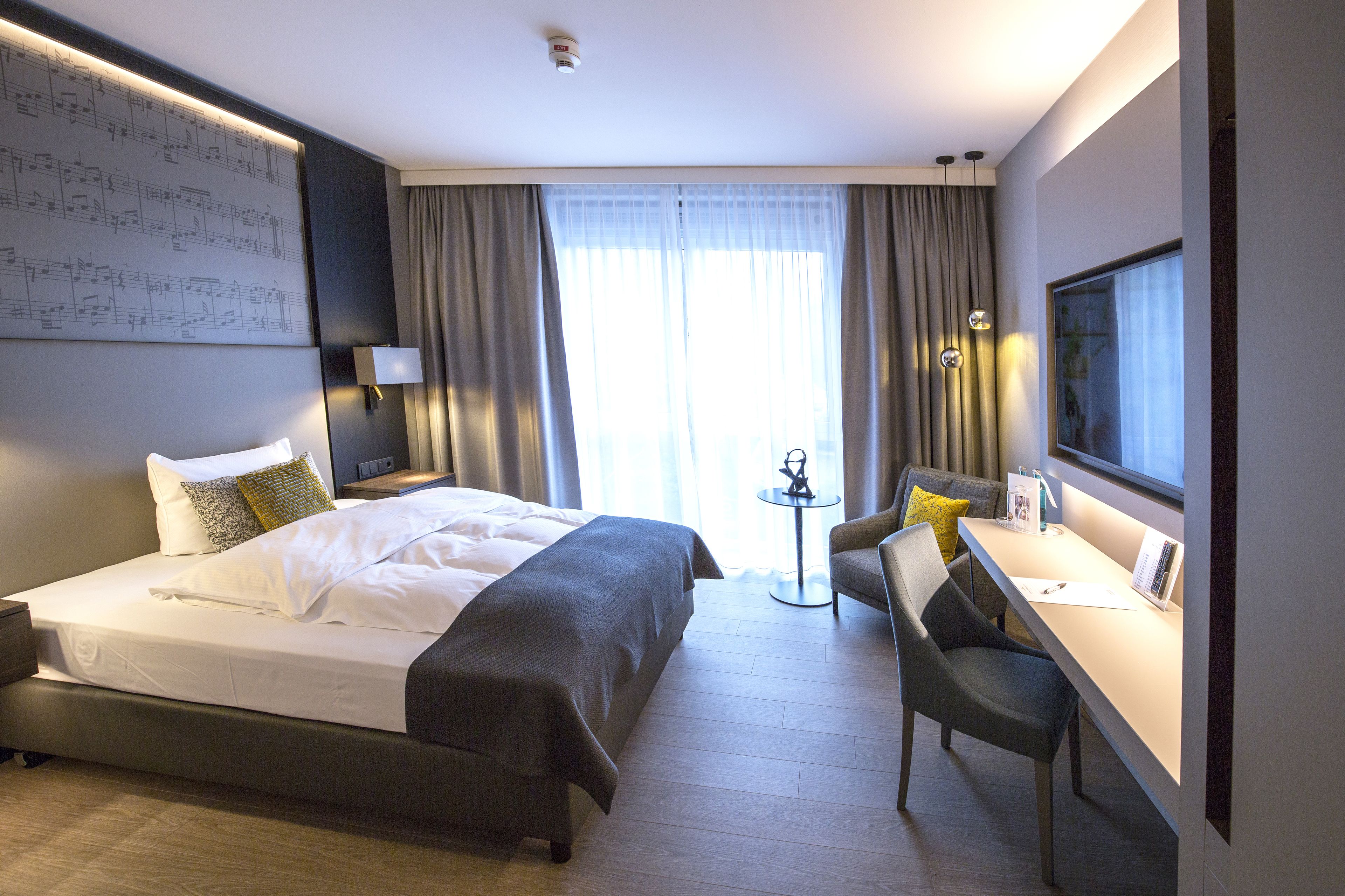 A modern hotel room with a large bed, a desk, and a television.