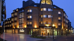 A modern hotel with a curved entrance, multiple windows, and a well-lit facade. - Kranz Parkhotel (Siegburg)
