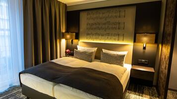 Un letto grande con una testiera scura, due comodini con lampade, un'opera d'arte appesa al muro e un tappeto decorato.