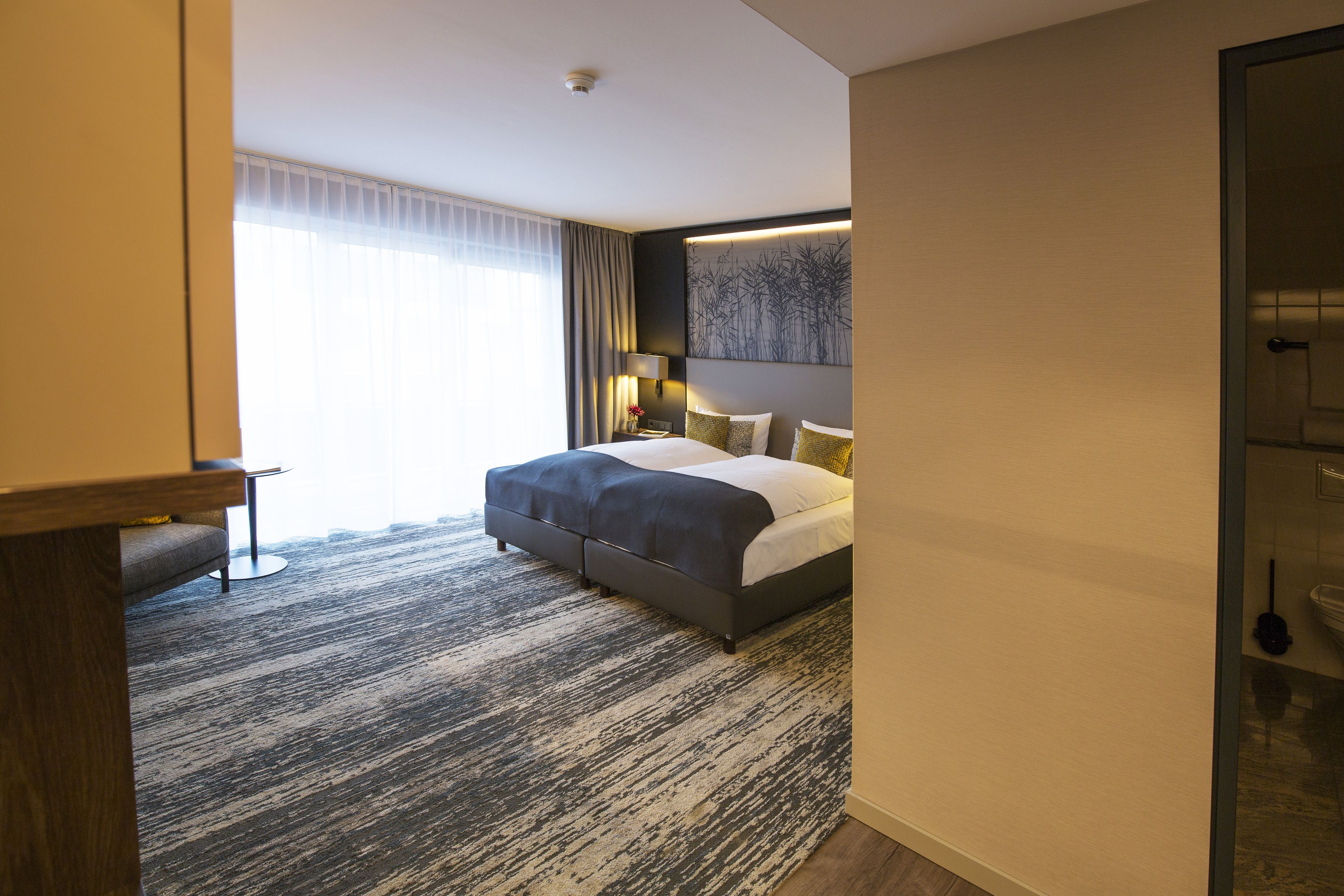 Une chambre d’hôtel moderne avec un grand lit, un bureau et une vue sur la ville.