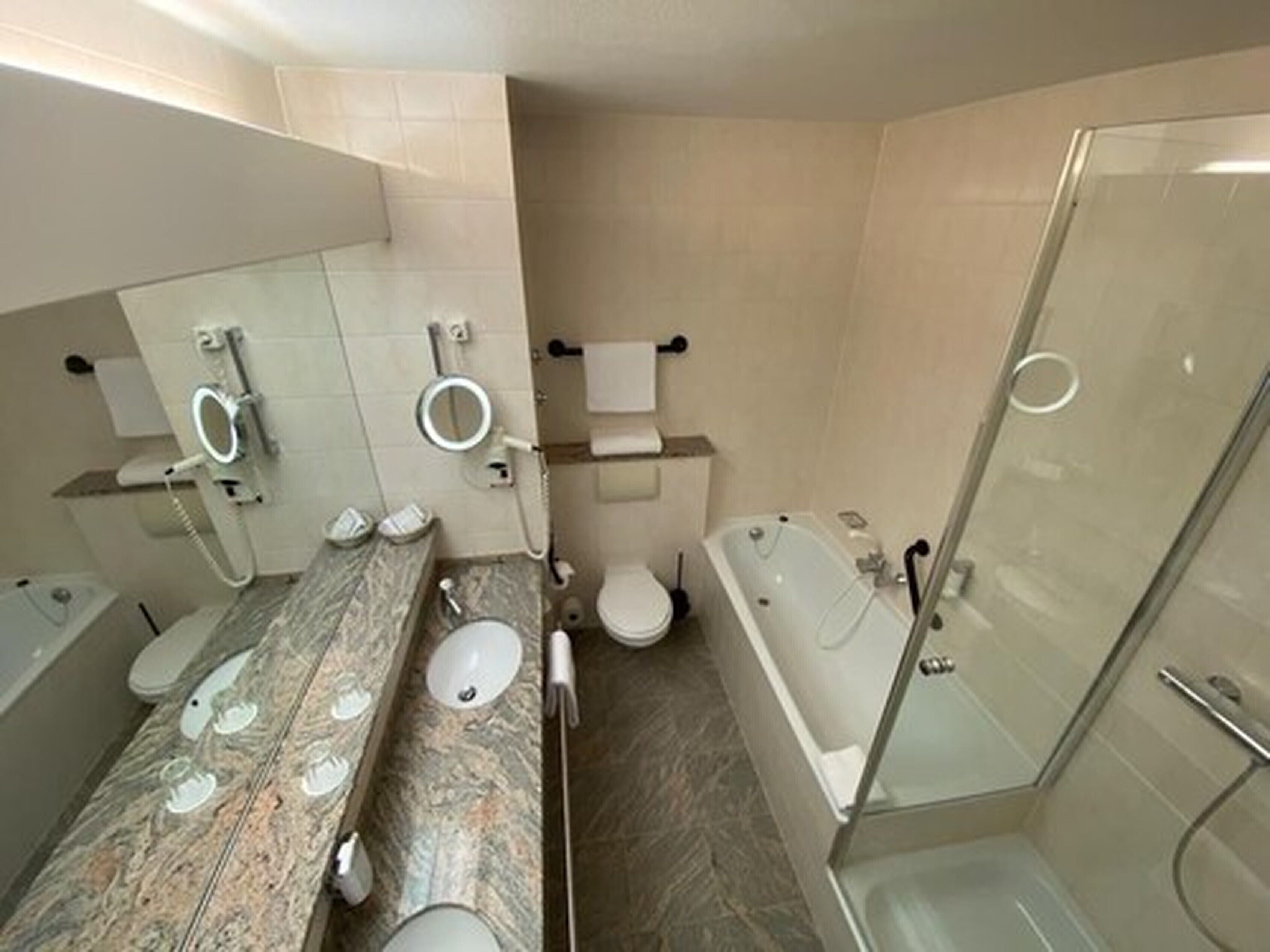 A modern bathroom with a marble vanity, a bathtub, and a glass shower enclosure.