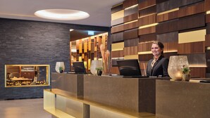 A modern reception desk with a laptop, a large vase, and a potted plant. - Kranz Parkhotel (Siegburg)