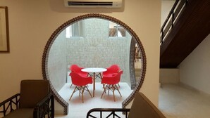 A room with a round mirror reflecting a dining area with a white table and red chairs. - Villa 8M by Gingerflower Boutique Hotel (Malacca City)
