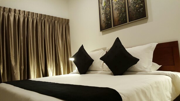 A neatly made bed with white and black bedding, a wooden headboard, and a large window with curtains. - Villa 8M by Gingerflower Boutique Hotel (Malacca City)