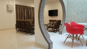 A living area with a sofa, chairs, a TV, and a dining table. - Villa 8M by Gingerflower Boutique Hotel (Malacca City)