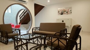 A modern living room with a brown sofa, black-framed chairs, a glass coffee table, and a large mirror. - Villa 8M by Gingerflower Boutique Hotel (Malacca City)