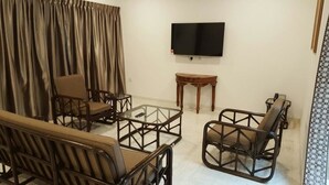 A living room with a TV, two armchairs, a coffee table, and a small wooden table. - Villa 8M by Gingerflower Boutique Hotel (Malacca City)
