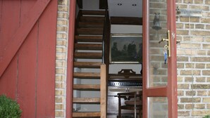 A rustic wooden door leading to a kitchen with a built-in oven and a wooden table.