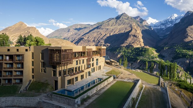 Un hotel moderno con varios pisos, piscina y vistas a las montañas.