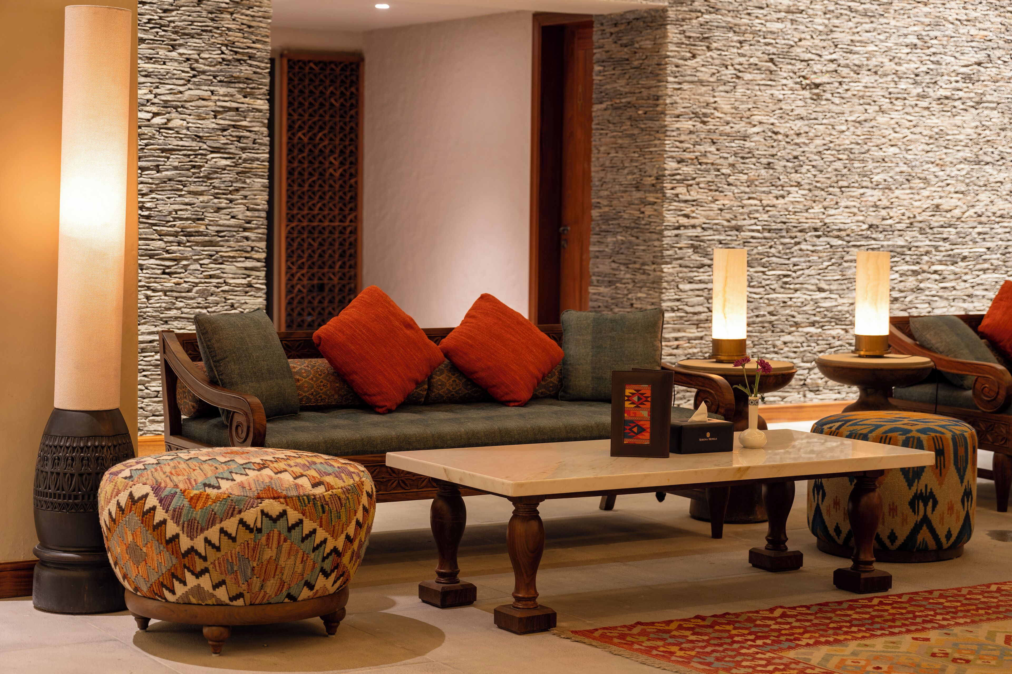A cozy seating area with a sofa, ottoman, and table, surrounded by stone walls and wooden accents.