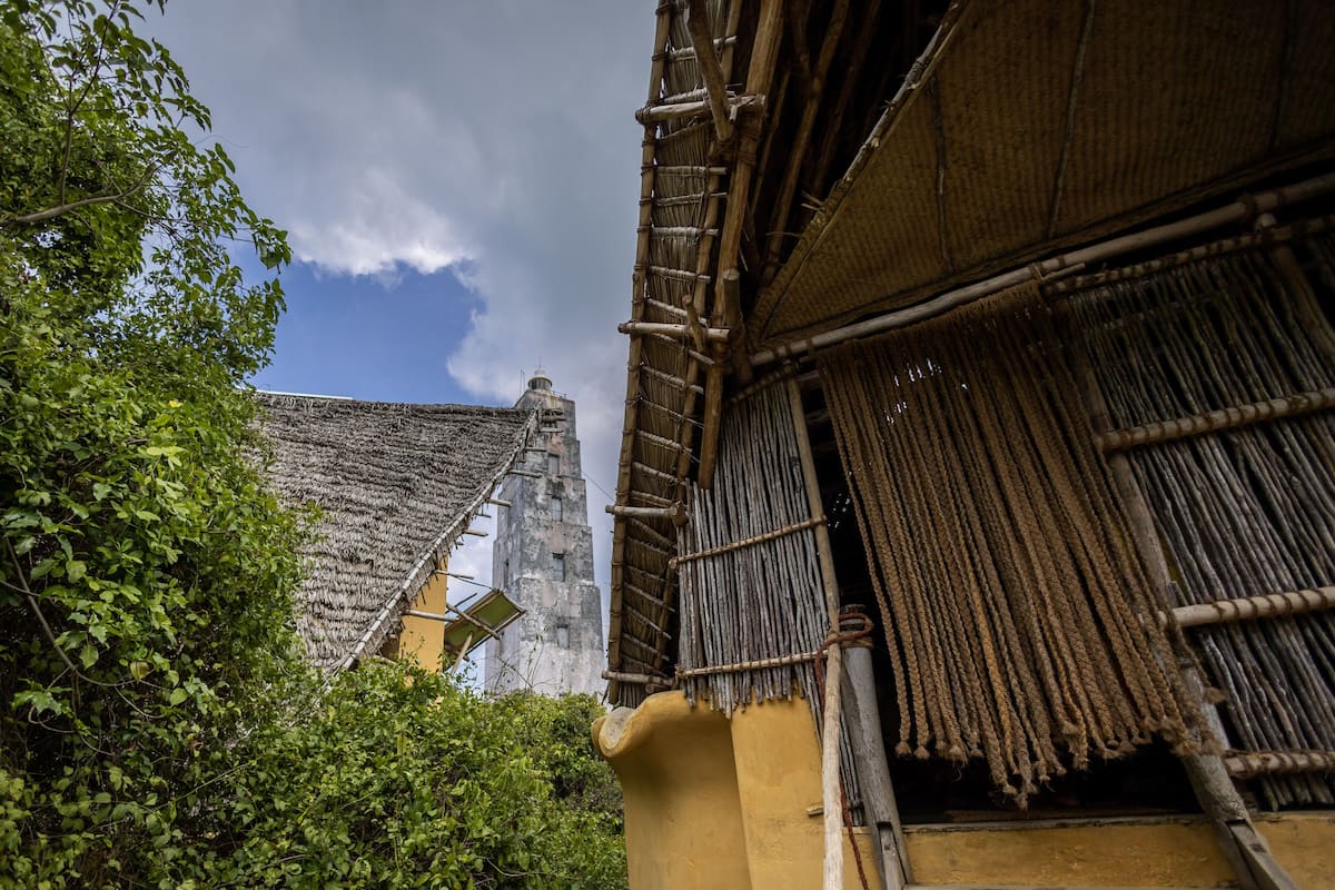 Un bâtiment traditionnel avec un toit de chaume, entouré de verdure.