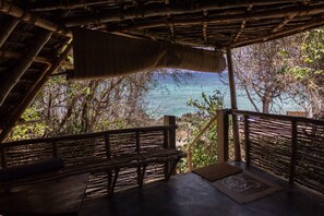 Une terrasse en bois offrant une vue sur la mer, entourée d’arbres.